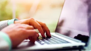 Person typing on a laptop outdoors.