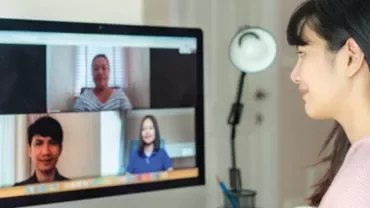 Woman participates in a video call with three colleagues on her computer screen.