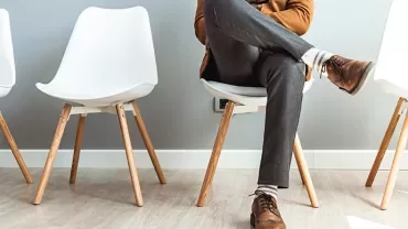 Person sitting on a chair in an empty waiting room.