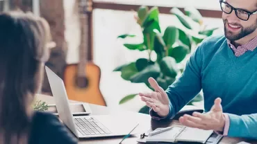 Man and woman having a discussion in an office with a laptop.