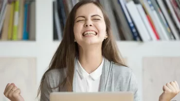 Woman celebrating success in front of laptop.