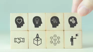 Wooden blocks with icons of heads representing ideas and teamwork.