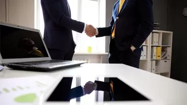 Two businesspeople shaking hands in a modern office.