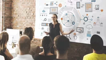 A woman giving a presentation on a social network diagram to a group of people.
