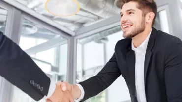 Smiling man in a suit shaking hands in an office.
