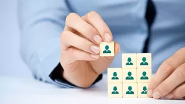Hand placing a block with an icon of a person on top of other blocks.