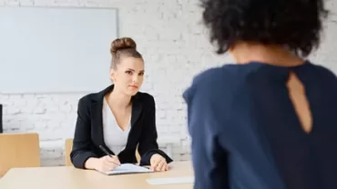 Two women in a professional meeting at a desk.