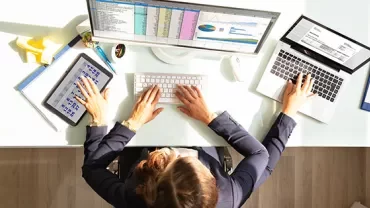 Person multitasking with tablet and laptop at desk