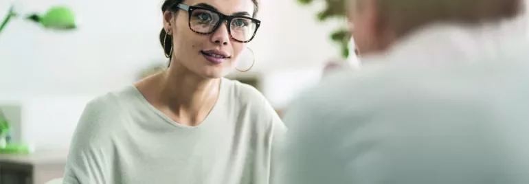 Woman with glasses attentively listening in a meeting.