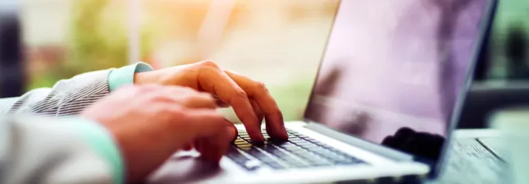 Person typing on a laptop outdoors.