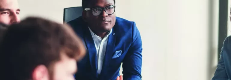 A man in a blue suit listens attentively during a meeting.