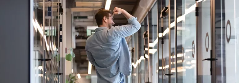 Man in hallway celebrating success with a fist pump.