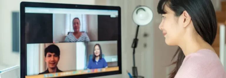 Woman participates in a video call with three colleagues on her computer screen.