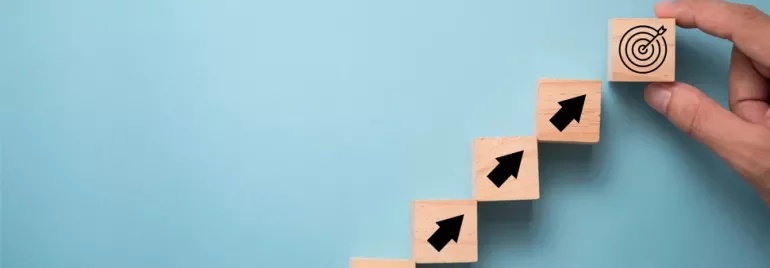 Hand placing target block after steps with arrows, blue background.