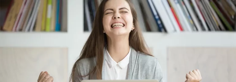 Woman celebrating success in front of laptop.