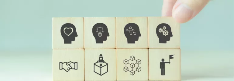 Wooden blocks with icons of heads representing ideas and teamwork.