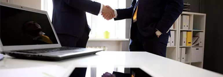 Two businesspeople shaking hands in a modern office.