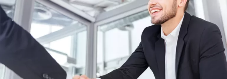Smiling man in a suit shaking hands in an office.