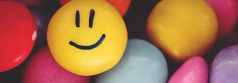 Colorful candies with a yellow smiley face candy in the center.