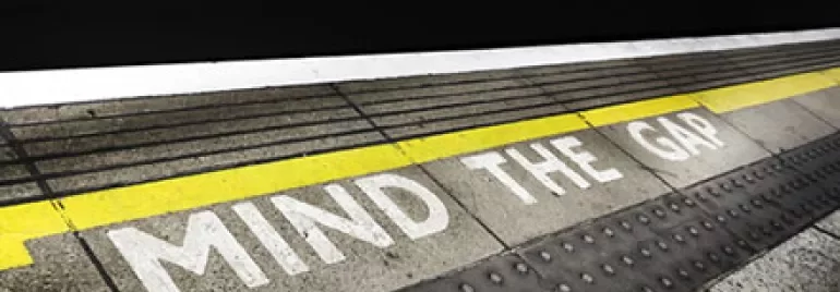 Platform edge with 'Mind the Gap' warning at a train station.