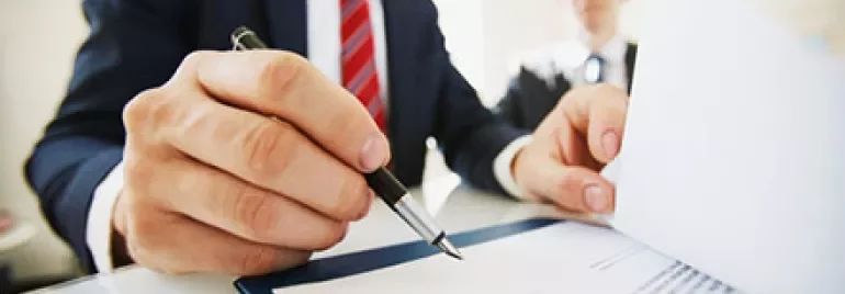Businessman signing a document at a desk.