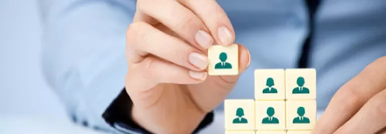 Hand placing a block with an icon of a person on top of other blocks.