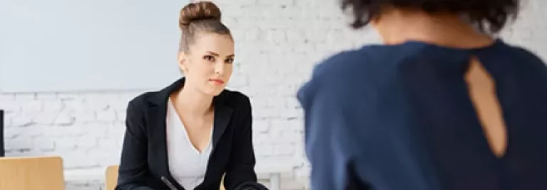 Two women in a professional meeting at a desk.