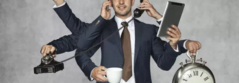 Businessman multitasking with phone, clock, and tablet.